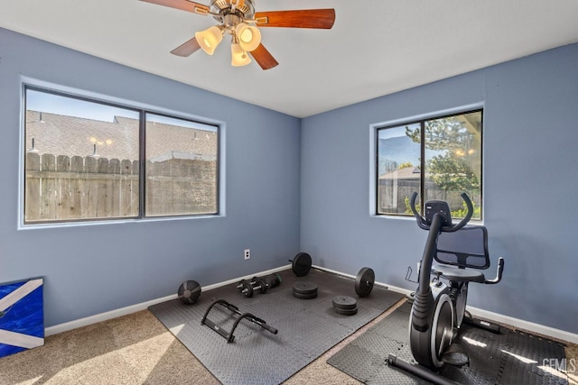 exercise area with a ceiling fan, baseboards, and a healthy amount of sunlight