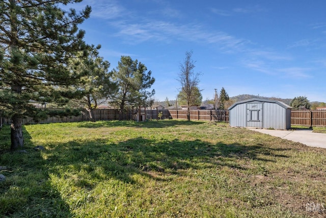 view of yard featuring an outdoor structure, a fenced backyard, and a storage unit