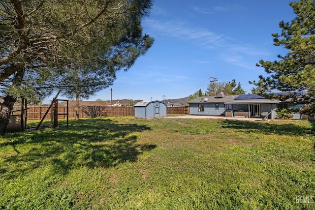view of yard with an outdoor structure, a patio, a fenced backyard, and a storage unit