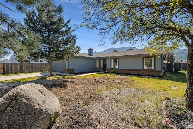 rear view of house with fence, a chimney, and brick siding