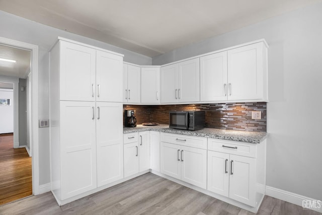 2104 B St, Bakersfield, CA 93301 - kitchen featuring black microwave, light wood-style floors, tasteful backsplash, baseboards, and light stone counters