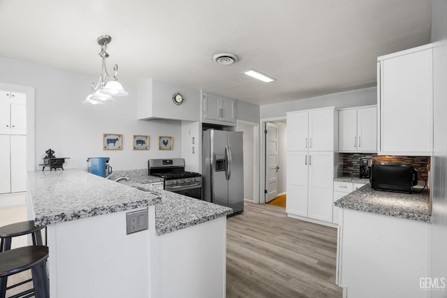 2104 B St, Bakersfield, CA 93301 - kitchen featuring appliances with stainless steel finishes, a peninsula, white cabinetry, and light stone countertops