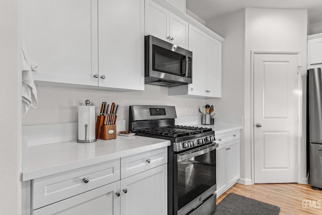 kitchen with stainless steel appliances, light wood-type flooring, and white cabinets