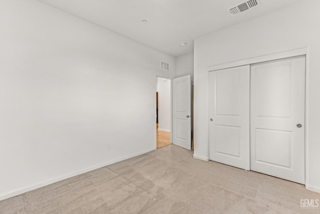 unfurnished bedroom featuring light colored carpet and a closet