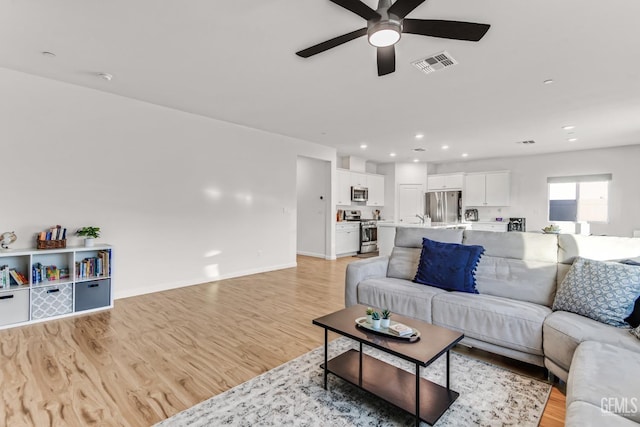 living room featuring ceiling fan and light hardwood / wood-style flooring