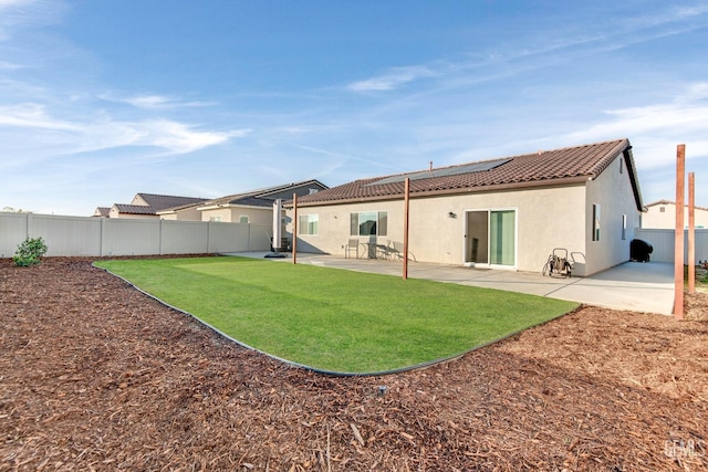 rear view of house featuring a yard, a patio area, and solar panels