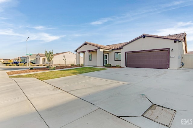 view of front of property featuring an attached garage, a tiled roof, concrete driveway, and stucco siding