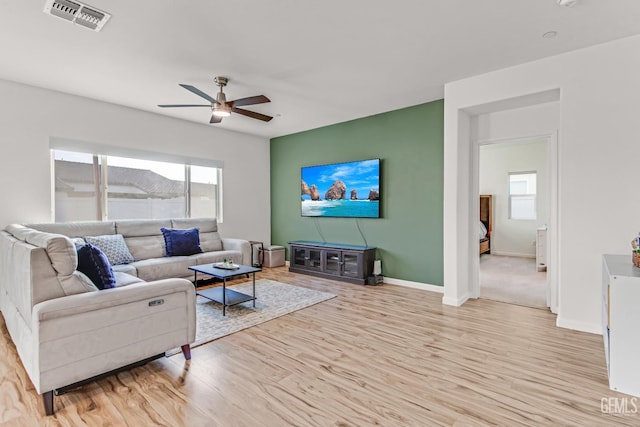 living room with a wealth of natural light, ceiling fan, and light wood-type flooring