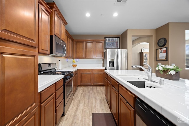 9318 Poseidon St, Bakersfield, CA 93306 - kitchen with stainless steel appliances, tile countertops, light wood-style flooring, brown cabinets, and recessed lighting