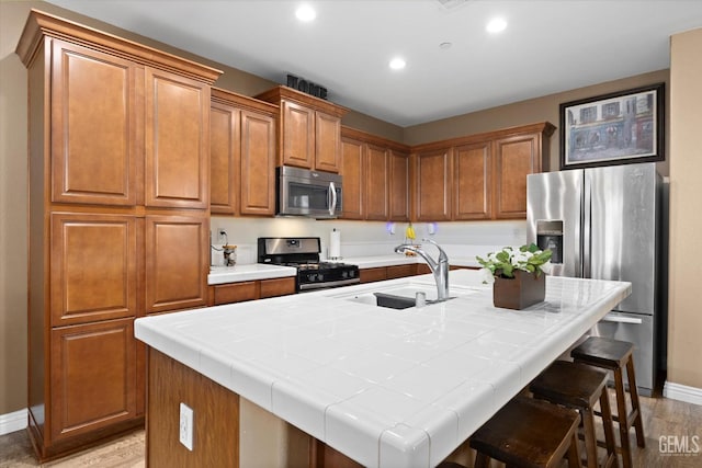 9318 Poseidon St, Bakersfield, CA 93306 - kitchen featuring stainless steel appliances, a kitchen island with sink, recessed lighting, brown cabinets, and a breakfast bar