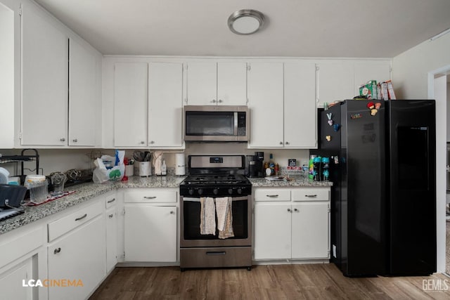 kitchen featuring stainless steel appliances, white cabinetry, and wood finished floors