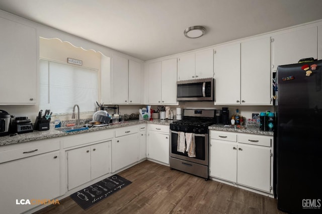 kitchen with stainless steel appliances, a sink, dark wood finished floors, and white cabinets