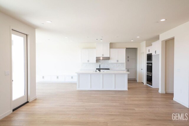 16615 Chloe Ct, Bakersfield, CA 93314 - kitchen with light countertops, backsplash, white cabinetry, light wood-type flooring, and under cabinet range hood