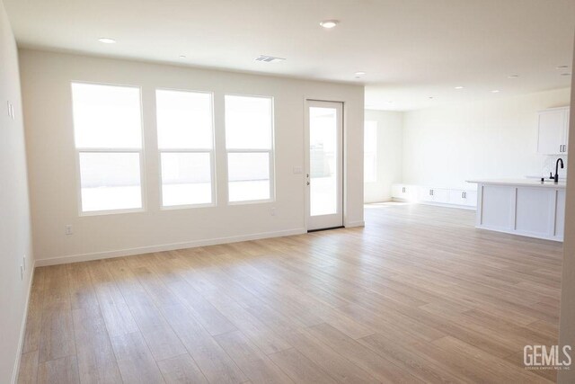 16615 Chloe Ct, Bakersfield, CA 93314 - unfurnished living room with visible vents, light wood-style floors, baseboards, recessed lighting, and a sink