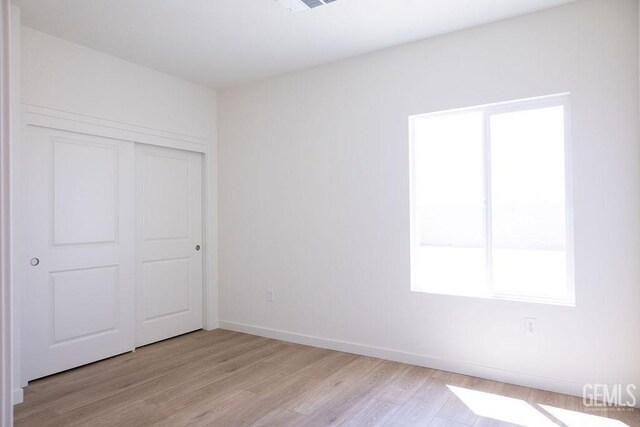 16615 Chloe Ct, Bakersfield, CA 93314 - unfurnished bedroom with a closet, baseboards, multiple windows, and light wood-type flooring