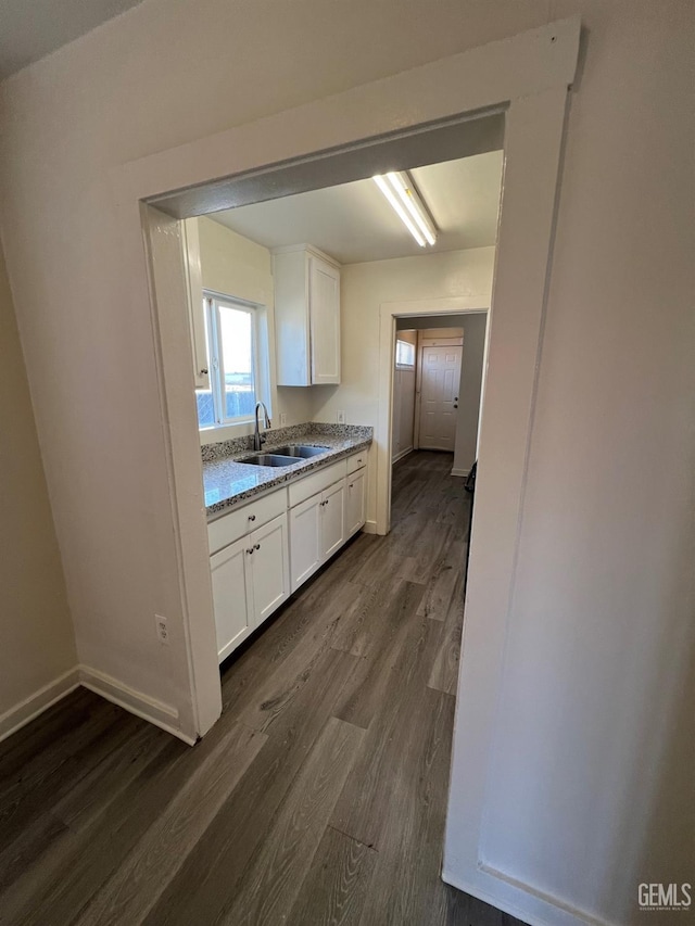 kitchen with sink, white cabinetry, light stone counters, and dark hardwood / wood-style floors