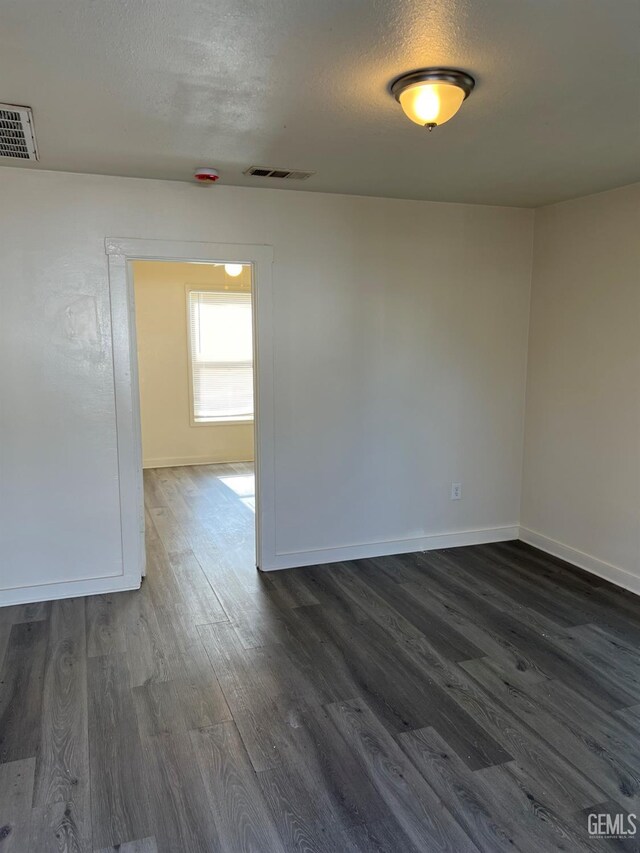 empty room featuring dark wood-type flooring and a textured ceiling