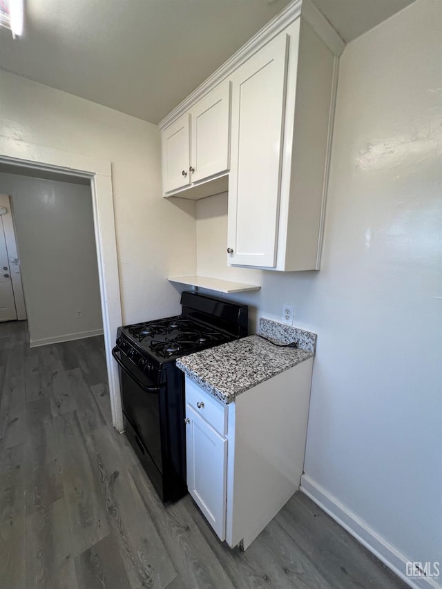 kitchen featuring black gas range oven, white cabinetry, light stone counters, and dark hardwood / wood-style floors