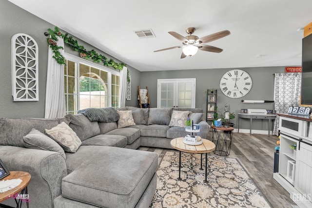 living area with ceiling fan, visible vents, and wood finished floors