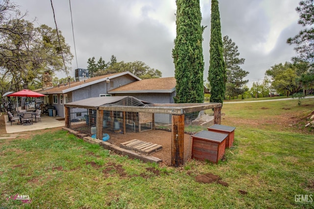 rear view of house with a lawn, exterior structure, a patio area, and an outbuilding