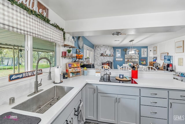 kitchen featuring gray cabinets, open shelves, a sink, light countertops, and a peninsula