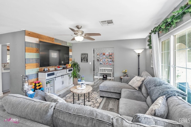 living area with visible vents, a ceiling fan, baseboards, and wood finished floors