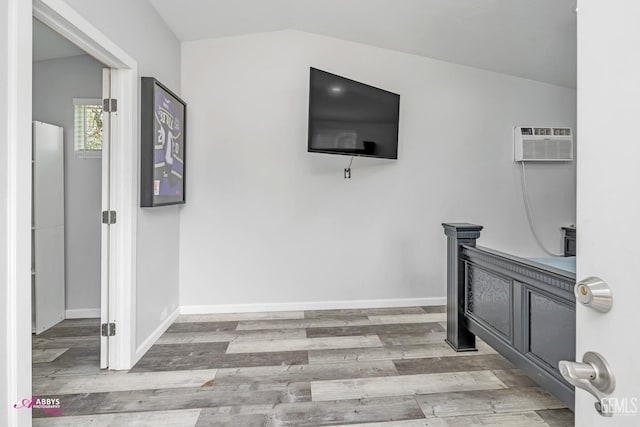 interior space with an AC wall unit, baseboards, and wood finished floors