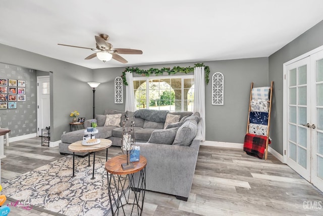 living room featuring baseboards, plenty of natural light, a ceiling fan, and wood finished floors
