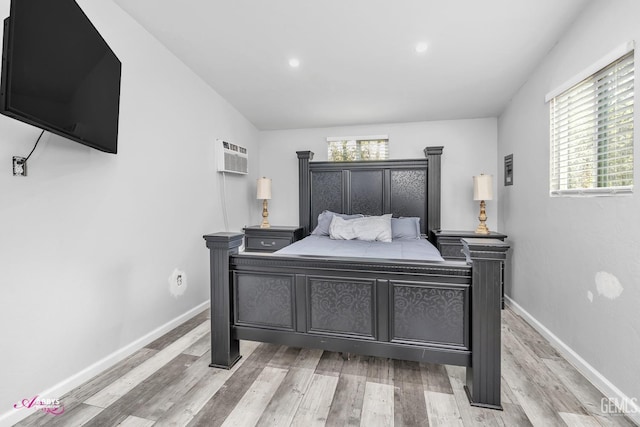 bedroom with recessed lighting, baseboards, a wall mounted AC, and light wood-type flooring