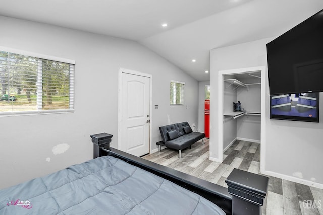 bedroom featuring wood finished floors, baseboards, a spacious closet, lofted ceiling, and recessed lighting