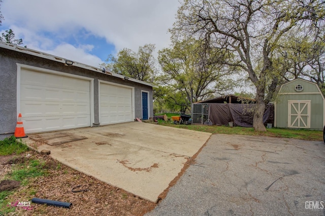 garage with driveway and a storage unit