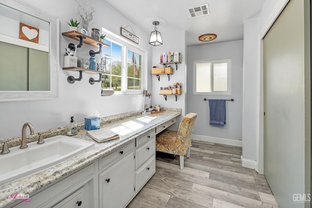 bathroom with baseboards, visible vents, wood finished floors, and vanity