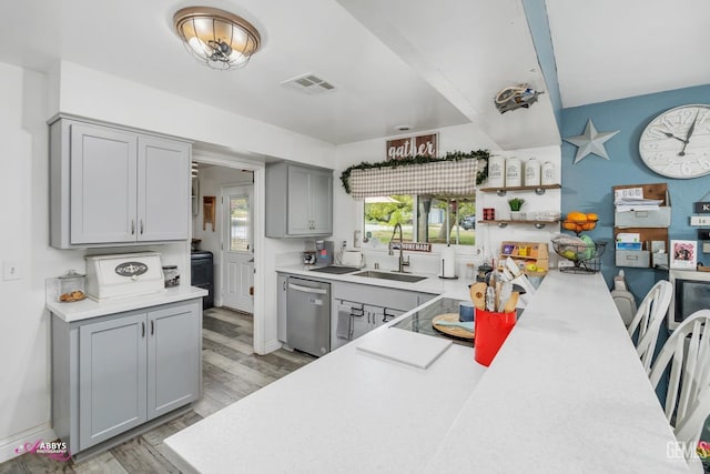 kitchen featuring visible vents, light wood-type flooring, dishwasher, a sink, and gray cabinetry