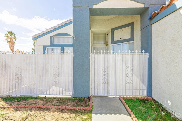 entrance to property with fence and stucco siding