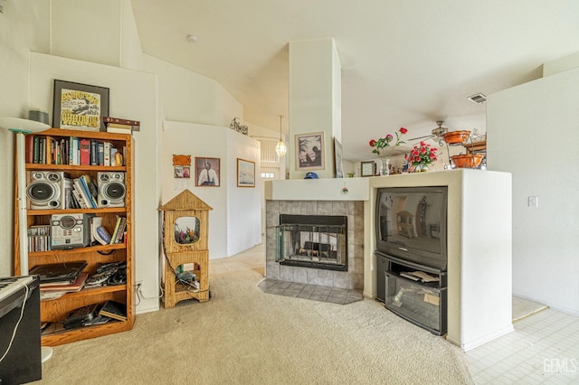 living area with carpet floors, visible vents, a tiled fireplace, a ceiling fan, and high vaulted ceiling