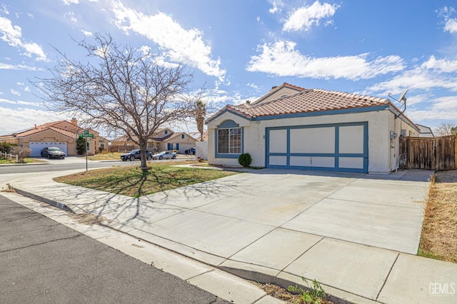 mediterranean / spanish-style home with driveway, a tiled roof, an attached garage, and stucco siding