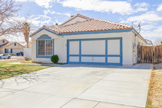 mediterranean / spanish house featuring a garage, a tile roof, fence, concrete driveway, and stucco siding