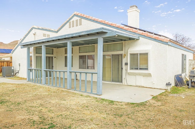 rear view of house with a patio area, a chimney, central AC, and stucco siding