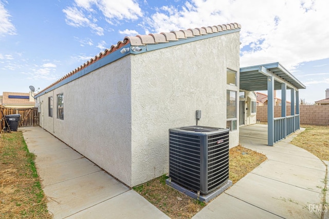 view of property exterior with central AC, fence, and stucco siding