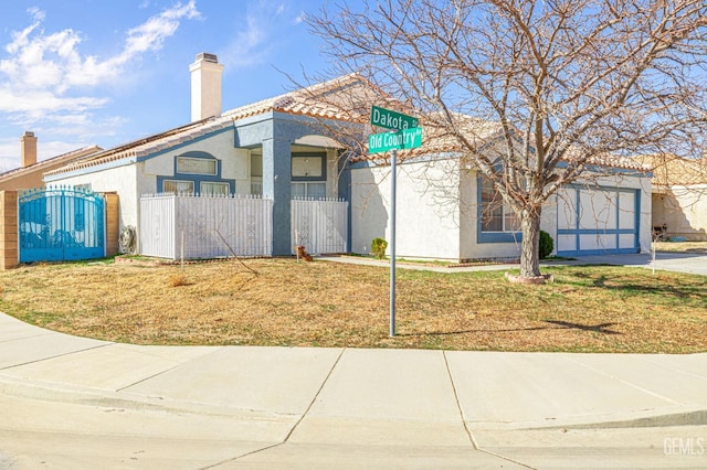 view of front facade with driveway, a fenced front yard, a chimney, a gate, and stucco siding