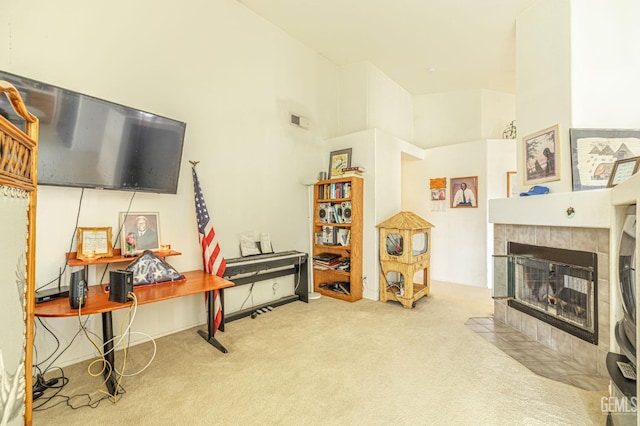 interior space featuring a tiled fireplace, a towering ceiling, and visible vents