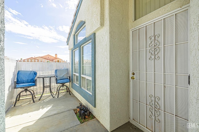 property entrance featuring a patio area, fence, and stucco siding