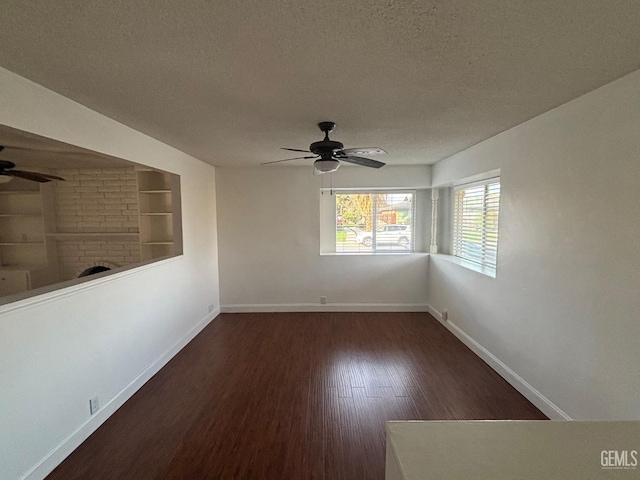 empty room featuring ceiling fan, dark hardwood / wood-style floors, a textured ceiling, and built in shelves