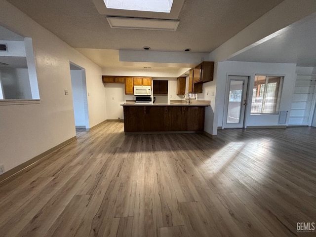 kitchen featuring a skylight, sink, kitchen peninsula, and hardwood / wood-style floors