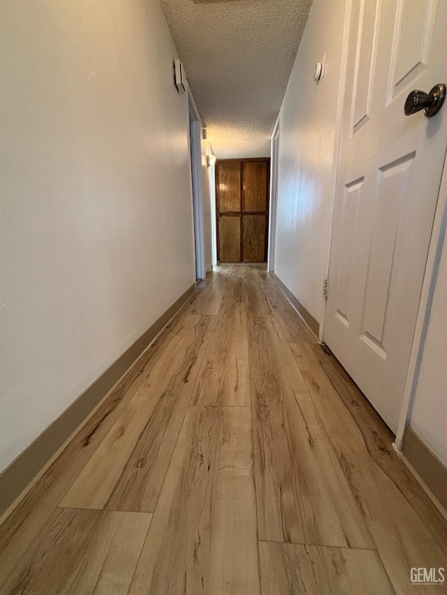 hall featuring a textured ceiling and light hardwood / wood-style flooring