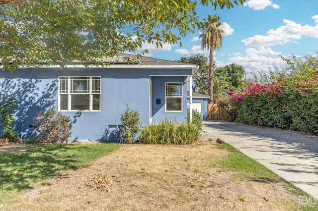 view of front of property with fence, a front lawn, and stucco siding