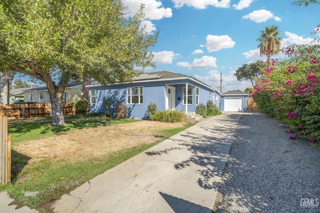 view of front of home with an outbuilding, fence, driveway, stucco siding, and a front lawn