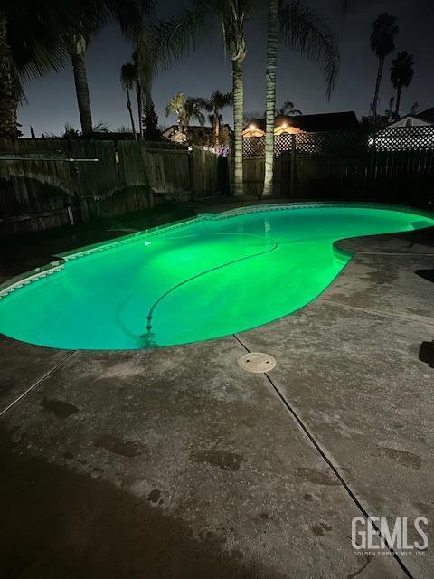 6100 Aruba Ct, Bakersfield, CA 93313 - pool at night with a fenced in pool, a patio, and a fenced backyard