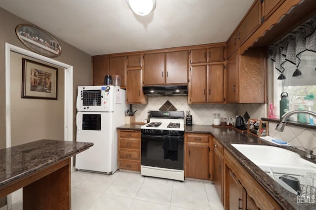 kitchen featuring light tile patterned flooring, white appliances, sink, and backsplash