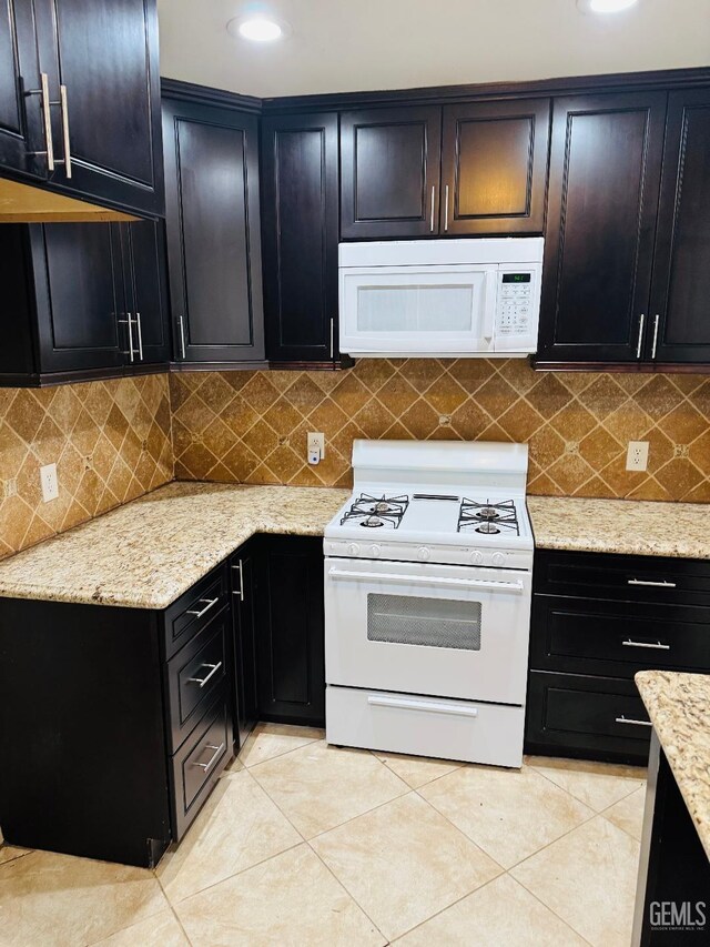 kitchen with light stone counters, white appliances, decorative backsplash, and light tile patterned floors